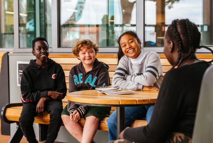 Image: A group of young people at a table smiling