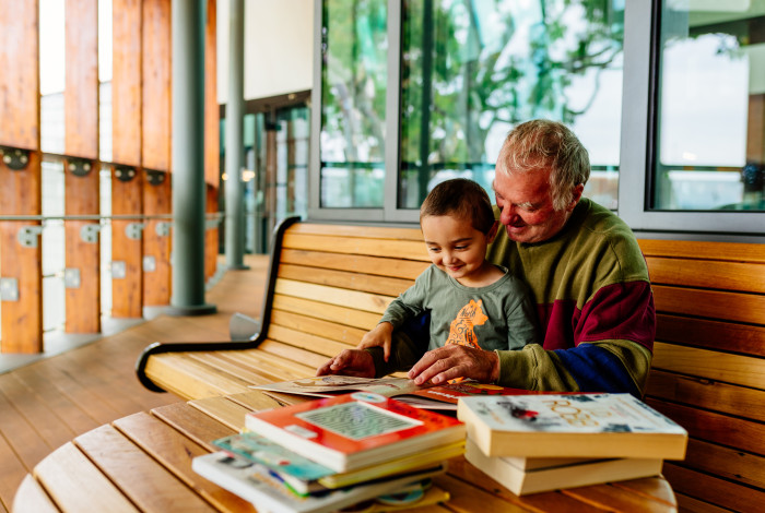 Image: Man reading a book to his grandchild at the library