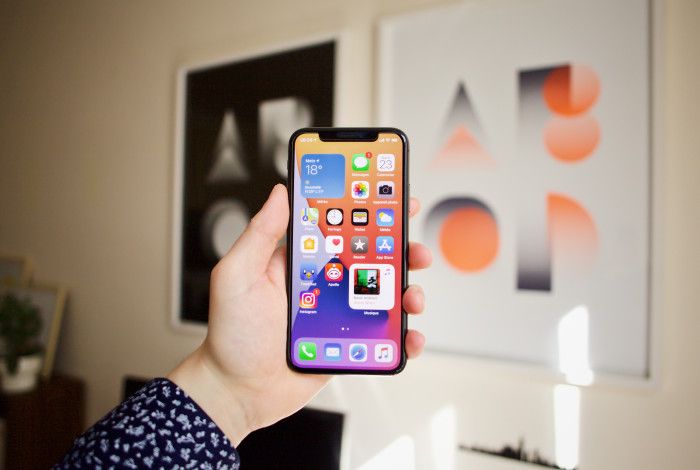 Image: A person holding a mobile phone in their hand with apps visible