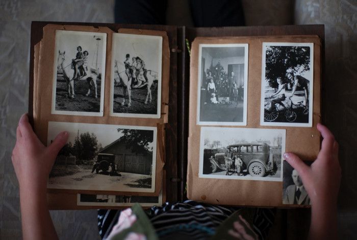 Image: A person holding up a photo album with old black and white photos.