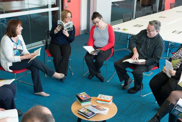 People sitting in a circle reading and discussing a book