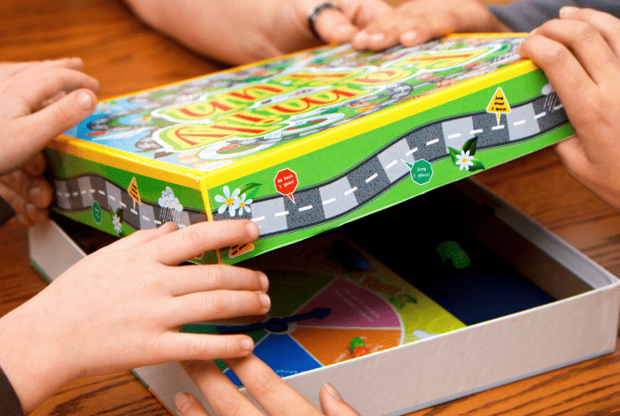 Board game on table being opened by several hands