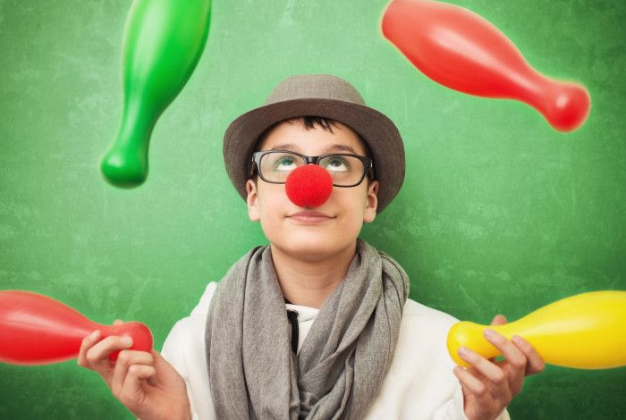 A person with a red clown nose juggling