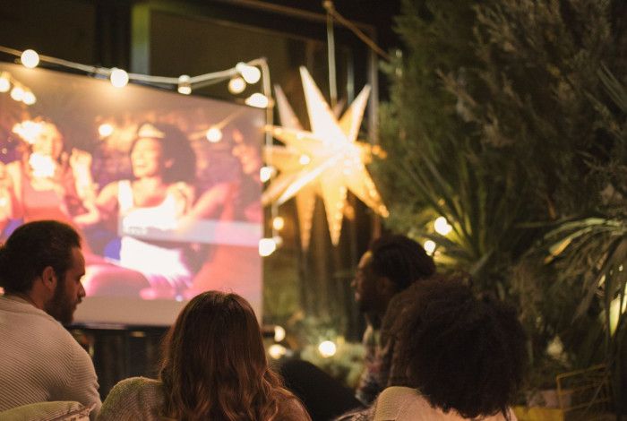 Group of people watching a movie on a screen outdoors.