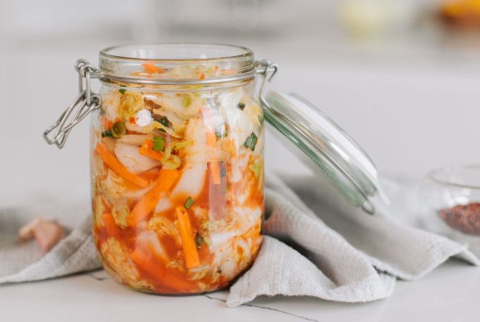 Jar of Kimchi open next to a garlic bulb.