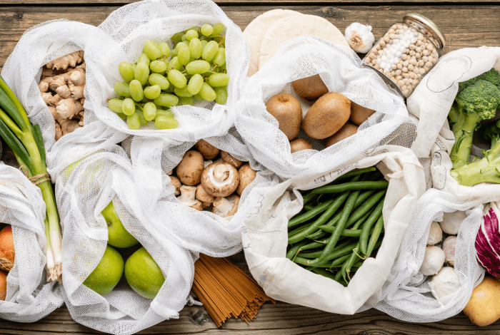 Fresh fruit and vegetables displayed in reusable produce bags.