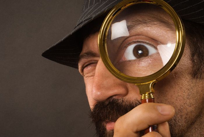 Detective looking through a magnifying glass.