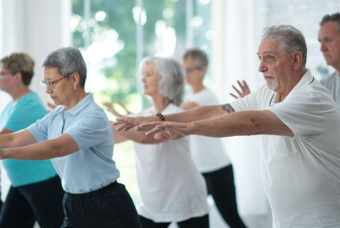 Group of older adults practicing Tai Chi in a bright, modern studio