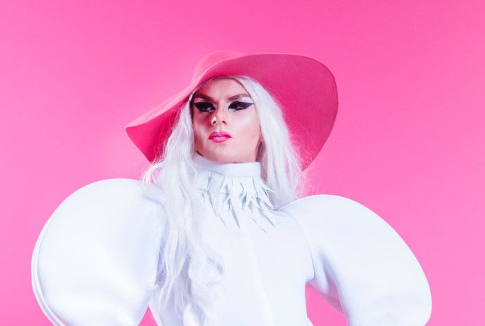 Drag queen with costume and large hat.