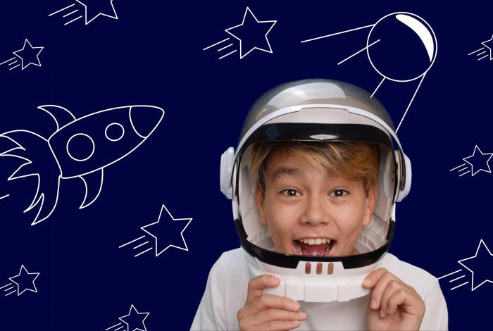 Child smiling wearing a space suit costume with a space themed background.