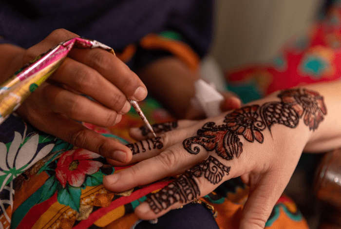 A person performing traditional henna art on hands.