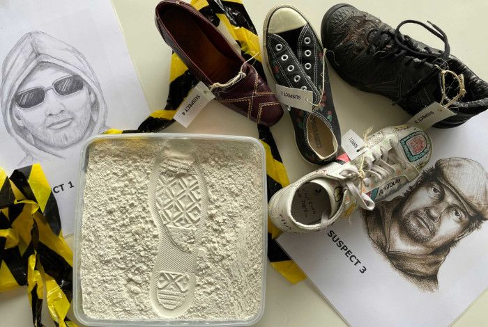 A forensic investigation setup showing a footprint impression in powder, five different shoes labeled with suspect numbers, and two suspect sketches on a white table with caution tape.