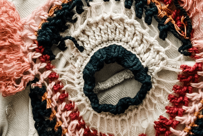 A chrocheted multicoloured circular item with abstract pattern.