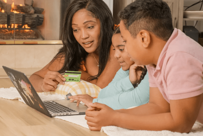 Mother and two children using laptop for online purchase.