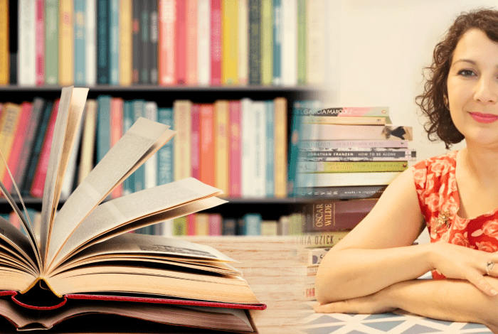 Author Sonya Tsakalakis with books in the foreground and on shelves in the background.