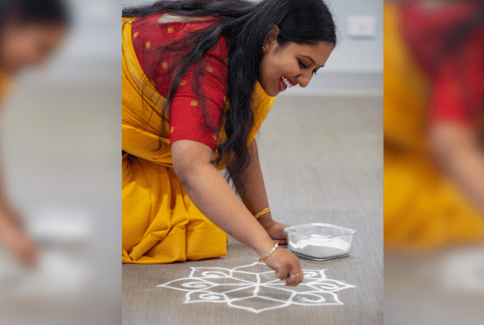 A lady drawing art on the ground with chalk.