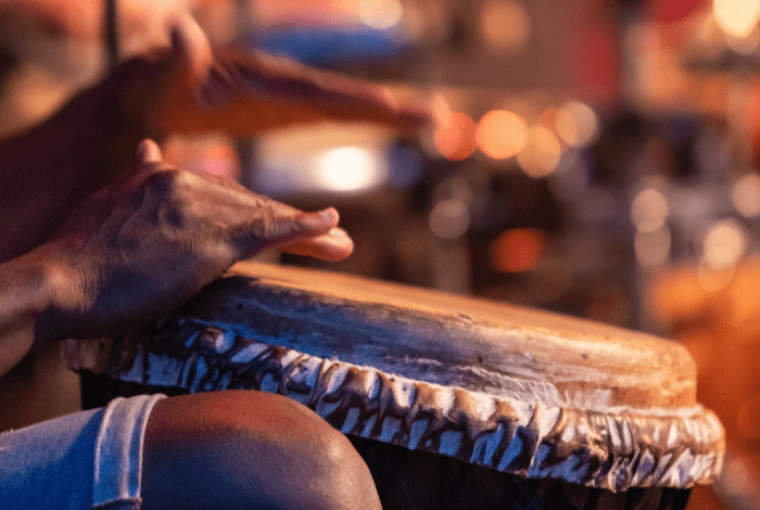 Closeup of person's hands drumming on a traditional drum.