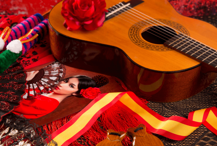 A photo of a young Spanish girl in traditional costume displayed together with a guitar and some other symbols of Spanish culture.