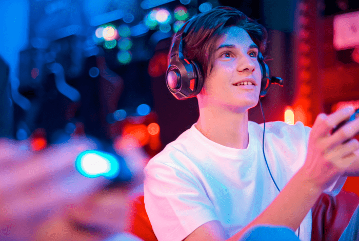 A boy with a gaming headset playing the PlayStation.