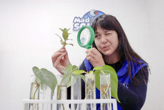 A woman looking through a magnifying glass at a plant.