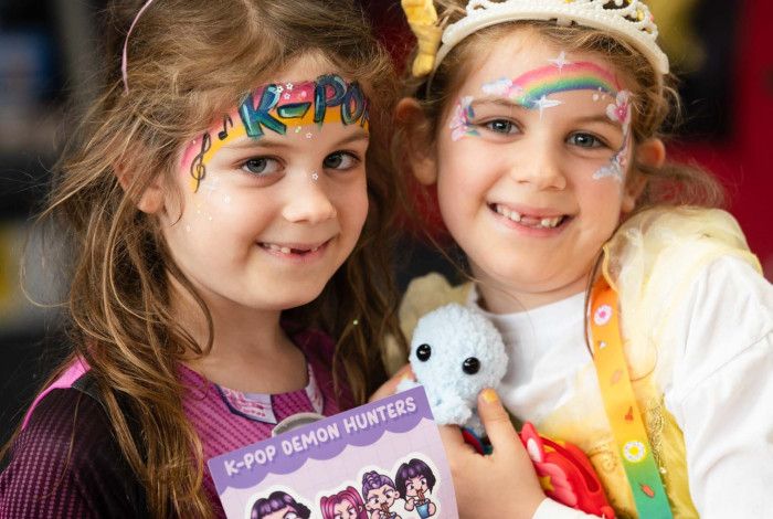 Two children with sheets of stickers in the library.