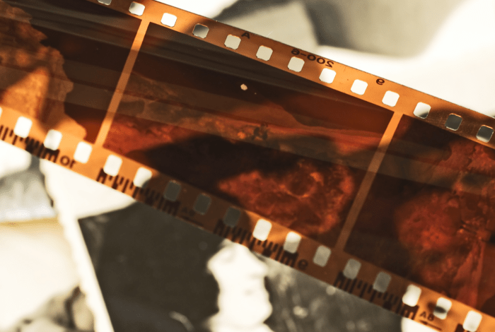 A photo film roll negatives viewed over the background of the black and white photos.