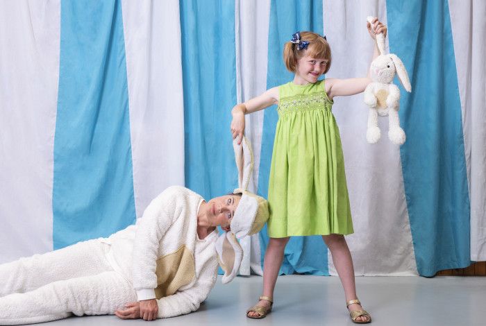 Child holding a soft toy rabbit with an adult in a rabbit costume.