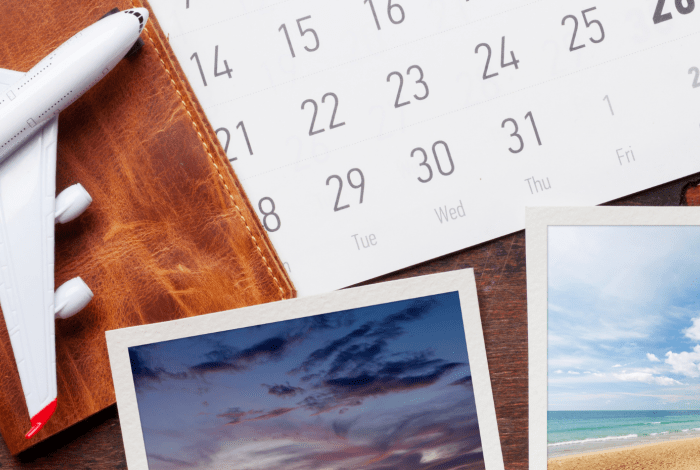 A travel-themed display featuring a calendar, printed photographs, a model airplane, and a notebook, highlighting memories, photography and planning.