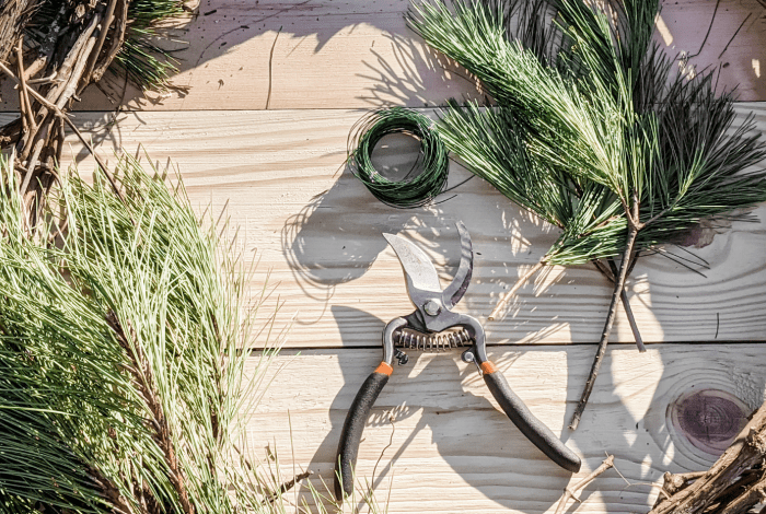 Pine branches, green gardening twine and secateurs displayed on the wooden surface.