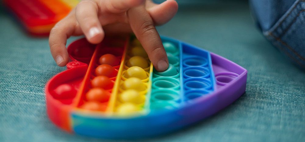 Heart shaped rainbow coloured sensory toy.