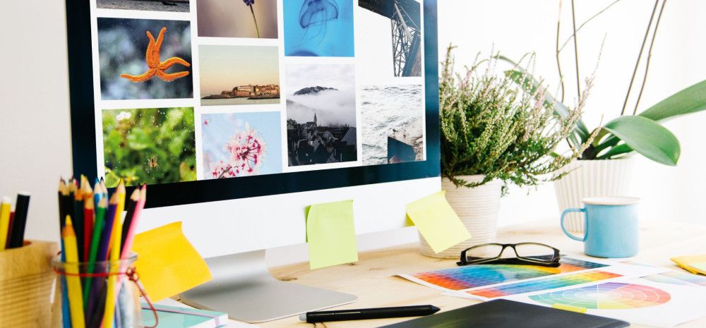 A computer displaying creative photography placed on a desk.