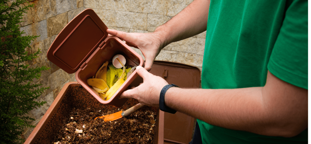 Person adding scraps to compost pile.