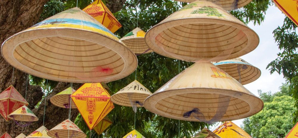 A mobile decoration created with traditional Vietnamese straw hats suspended on a string.