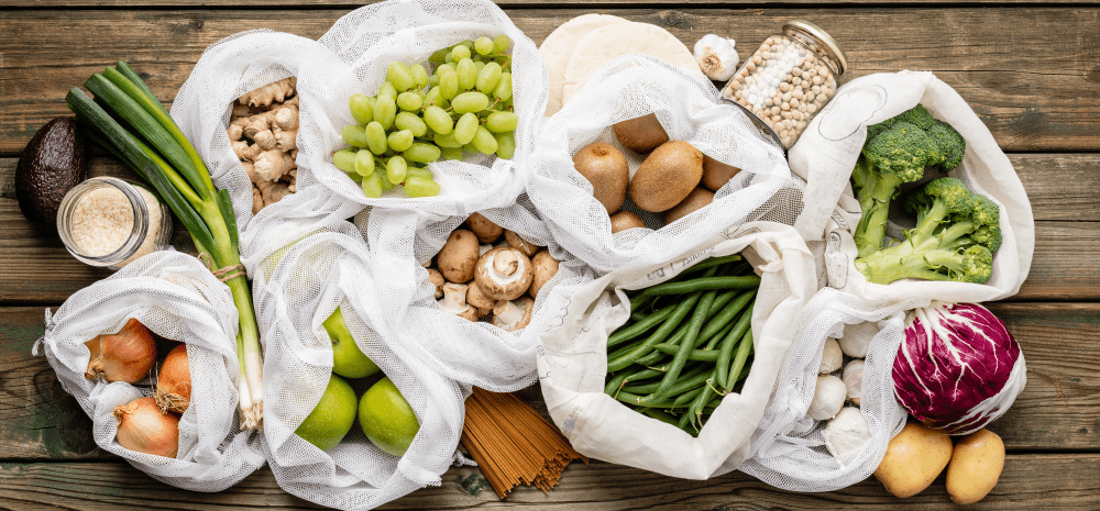 Fresh fruit and vegetables displayed in reusable produce bags.