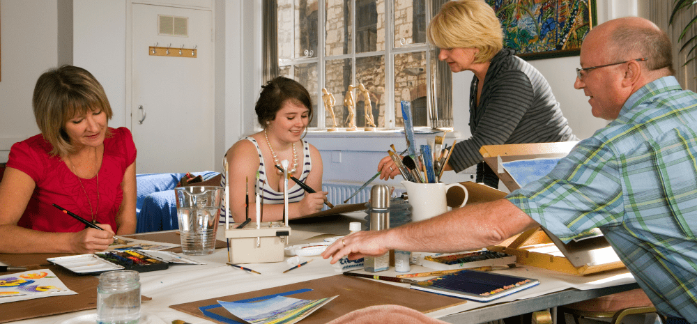 Art class with four people painting on paper.