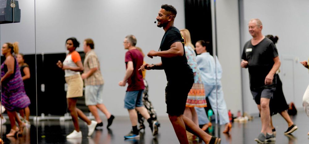 A salsa dancer leading a group in a class