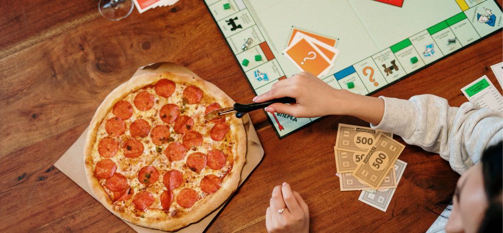 A pizza and set of board games on the table.