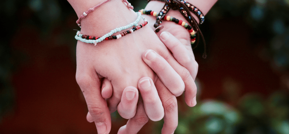 Holding hands wearing colourful friendship bracelets.