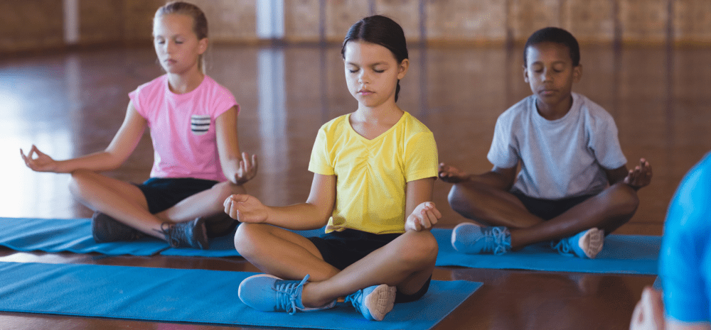 Children in lotus position during yoga session.