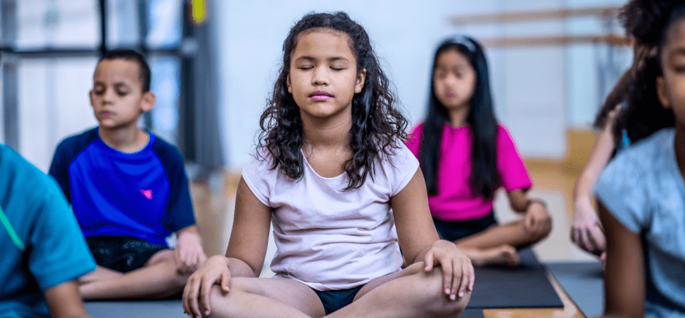 Children in lotus position during yoga session.