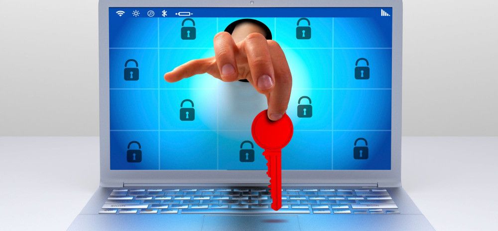 A hand reaching out of a laptop screen, holding a red key.