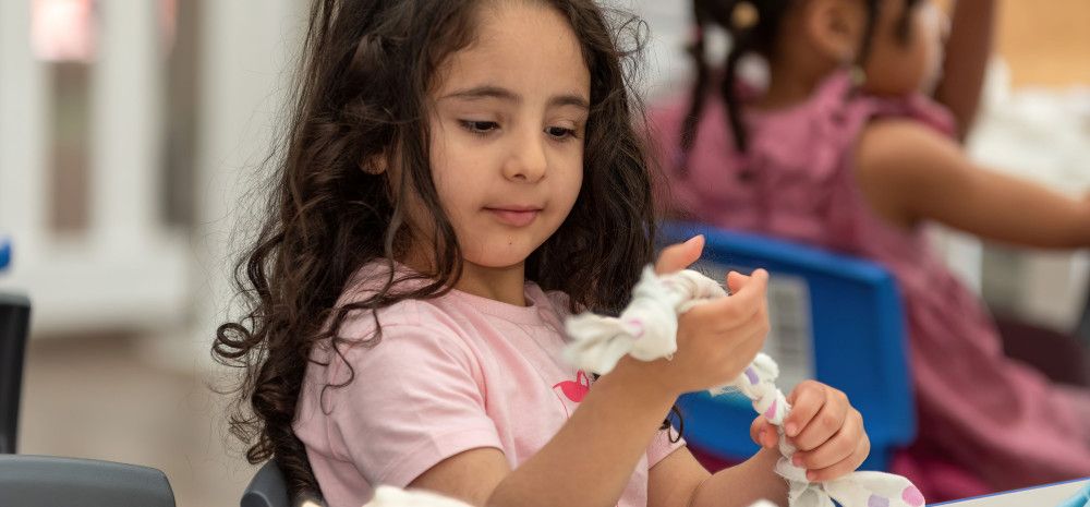 Child making a pet toy out of fabric.