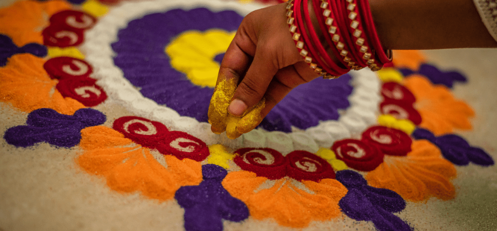 A hand holding coloured powder to create rangoli.