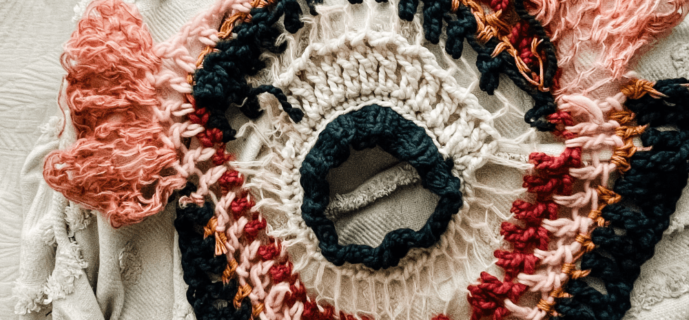 A chrocheted multicoloured circular item with abstract pattern.