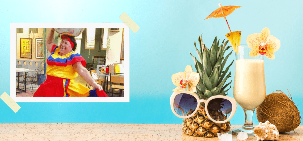 Postcard portraying a Columbian woman with items on a table including a pineapple, coconut, shells and a cocktail.