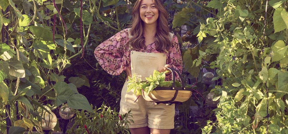 Author Connie Cao in the garden holding a basket of herbs.