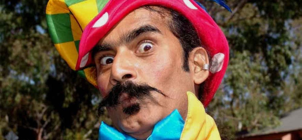 Man dressed as jester staring into the camera.