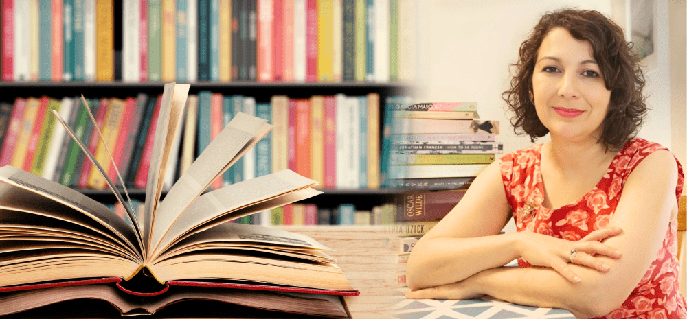 Author Sonya Tsakalakis with books in the foreground and on shelves in the background.