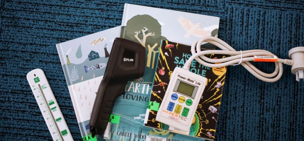 A thermometer, thermal imaging camera and Powermate set out on a library floor with library books.