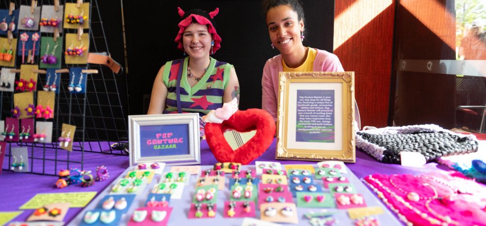 Two teenage girls sitting at the stall with creative colourful jewellery.
